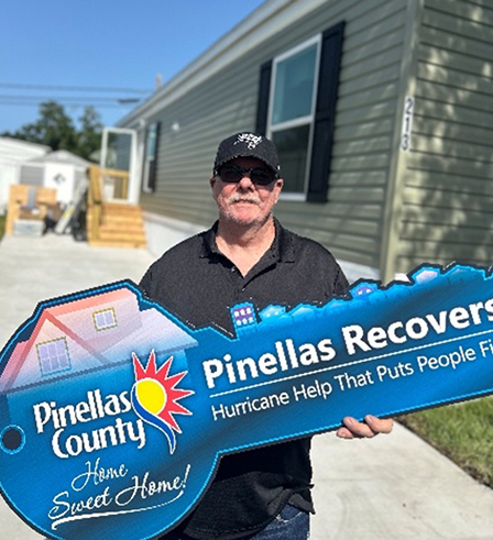 Richard shows off his Pinellas Recovers key outside his home.